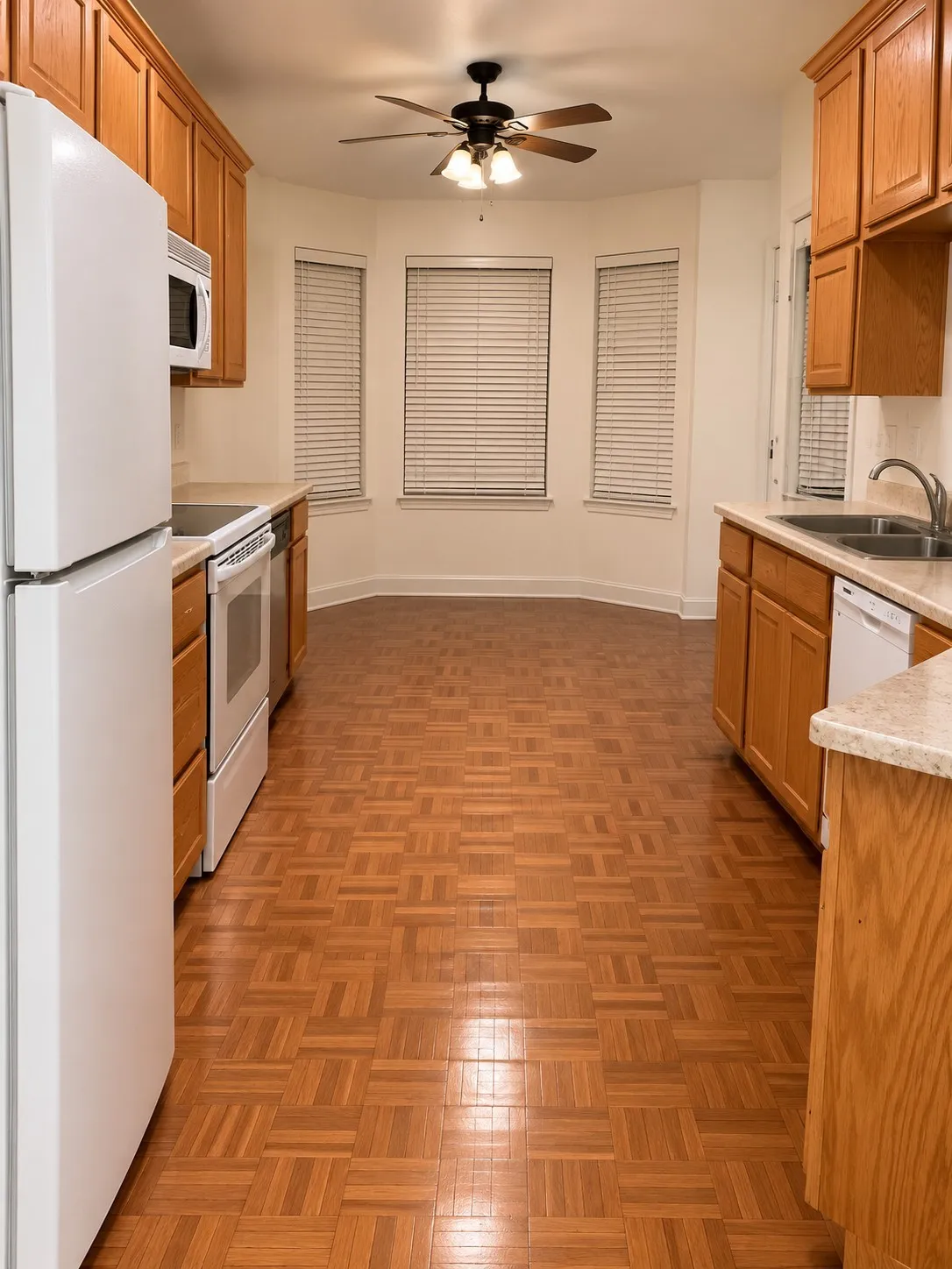 Kitchen featuring wood-finish flooring, oak cabinetry, white appliances, and a bay window
