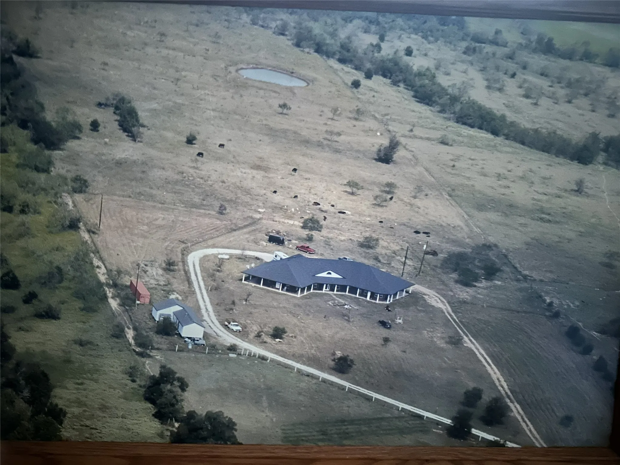 Expansive land parcel with a primary residence, additional structures, and a pond feature