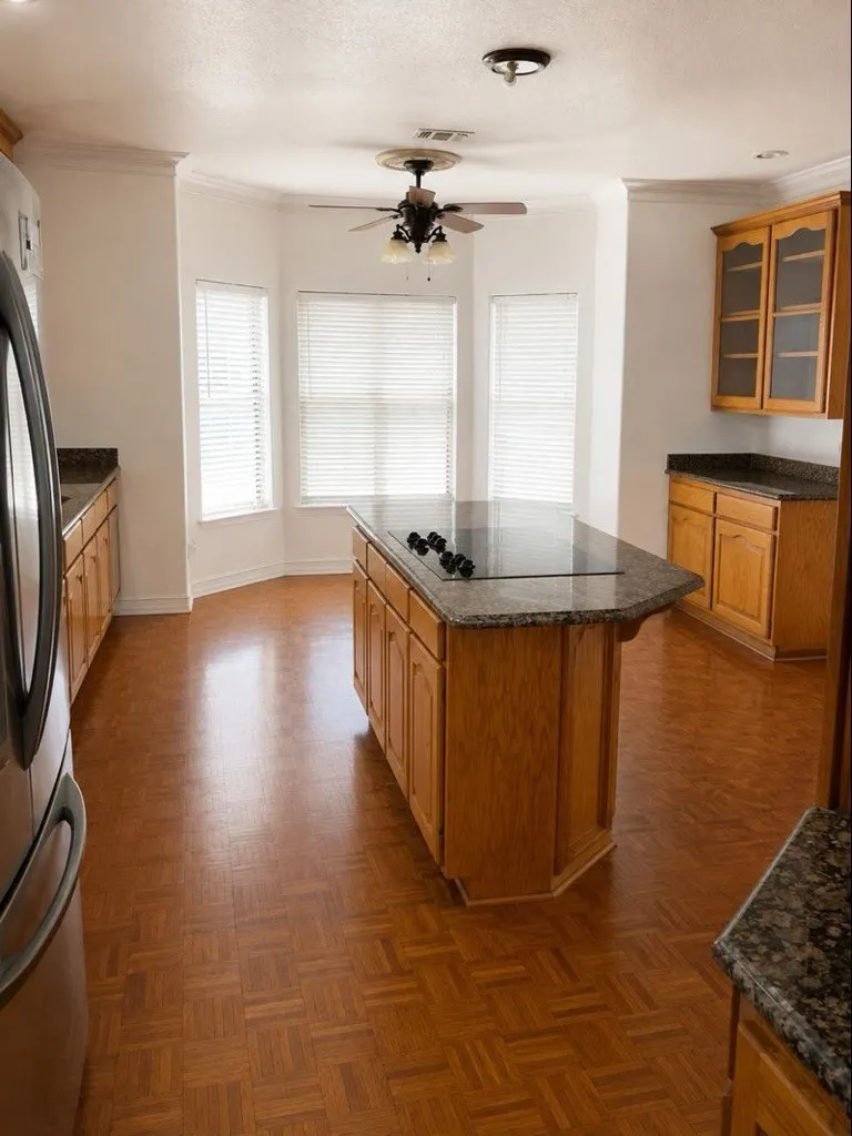 Kitchen featuring a central island with cooktop, granite countertops, wood-finish flooring, and light wood cabinetry