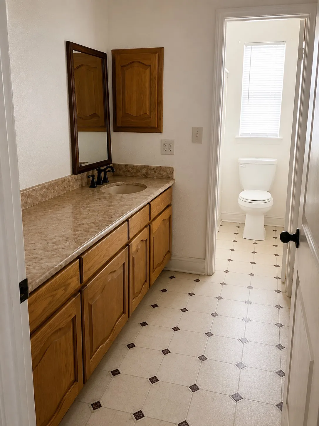 Extended vanity with a built-in sink, wood-finish cabinetry, and a framed wall mirror