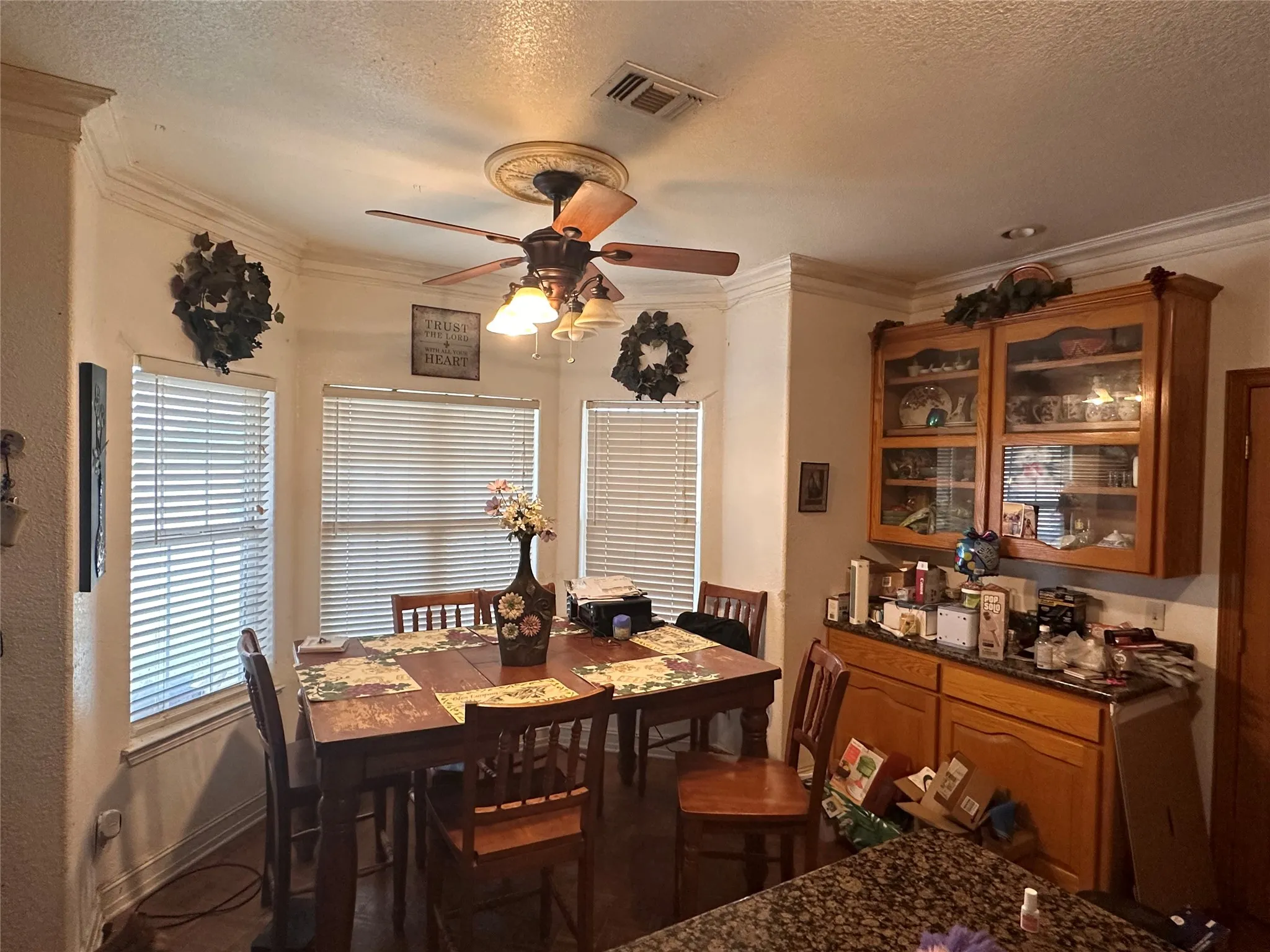 Dining area with a bay window, crown molding, and a ceiling fan