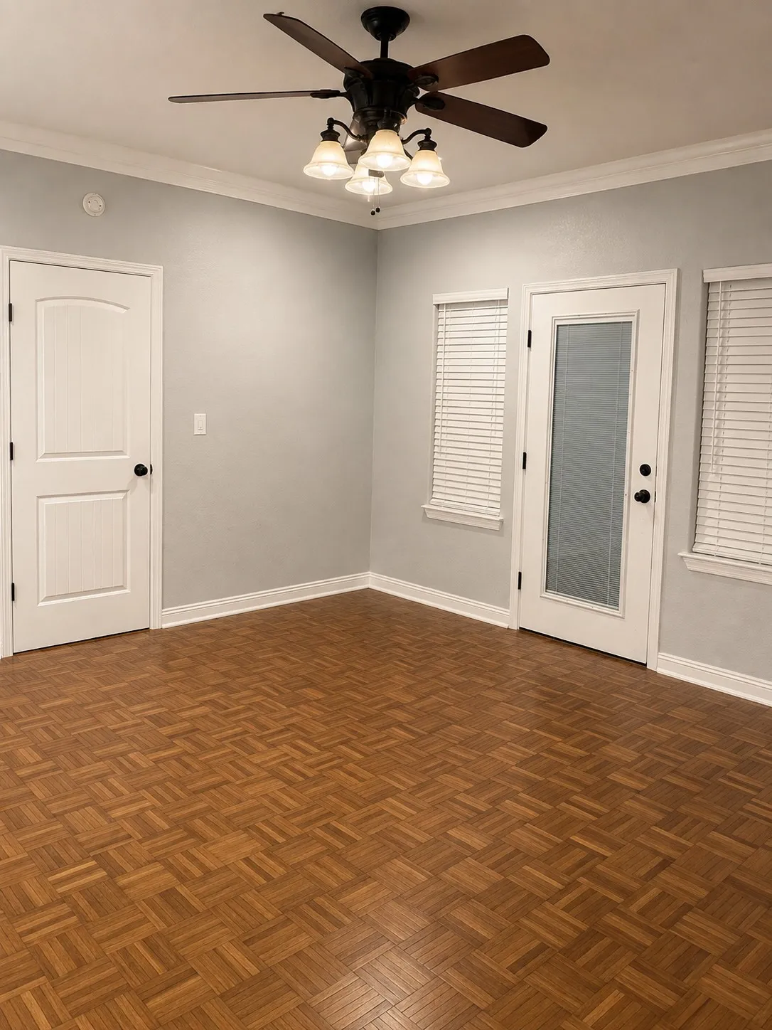 Wood-finish parquet flooring, white trim, crown molding, and a ceiling fan with integrated lighting