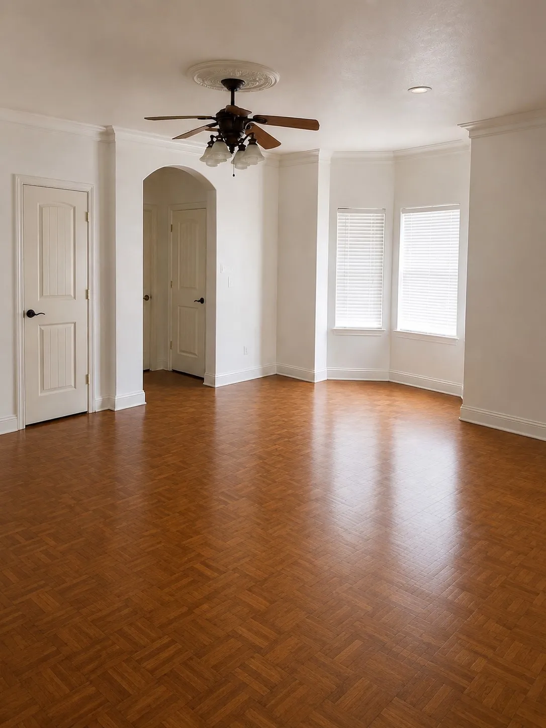 Parquet wood-finish flooring, bay windows with blinds, architectural archway, ceiling fan with decorative medallion, recessed lighting