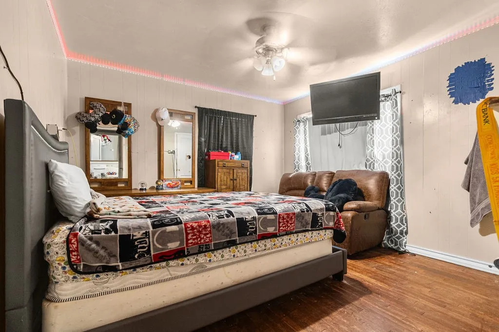 Hardwood flooring, ceiling fan with integrated lighting, and window with textile coverings