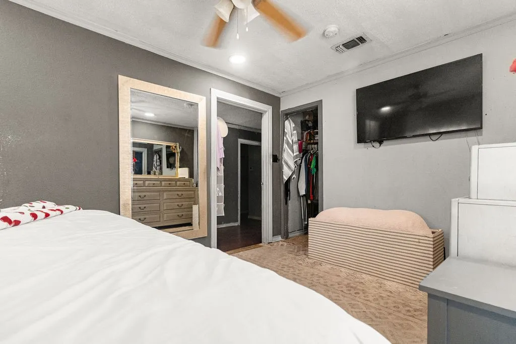 Recessed ceiling lighting, ceiling fan, carpet flooring, wall-mounted television, and a built-in closet