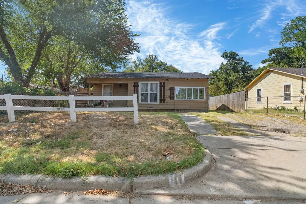 Single-story residence featuring a covered front porch, multiple windows, and a white picket fence