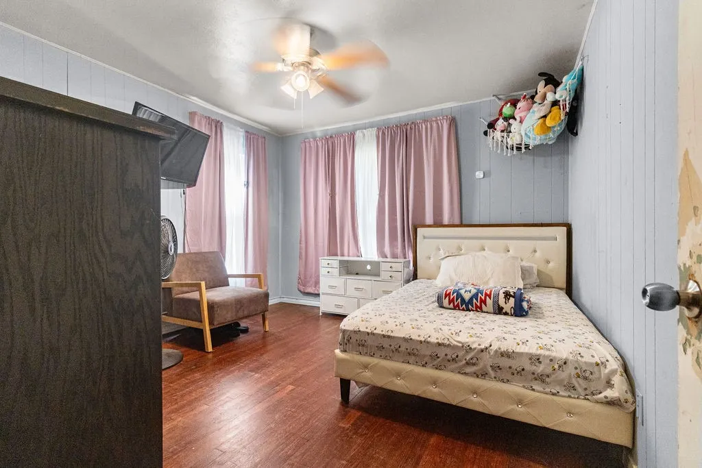 Wood-finish flooring with light blue vertical paneling and a ceiling fan