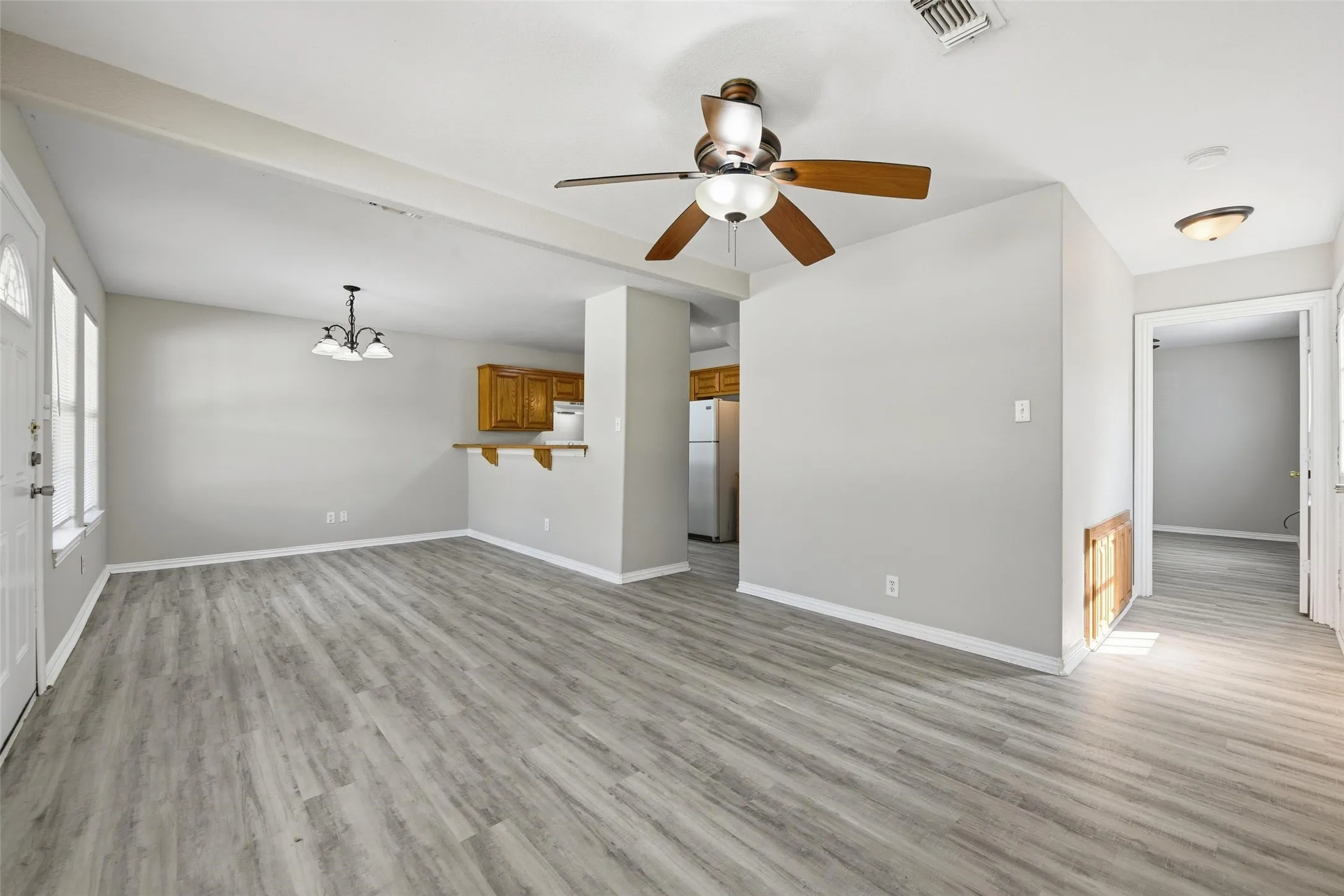 Wood-finish flooring throughout, light gray wall paint, kitchen with wood cabinetry and built-in breakfast bar, ceiling fan with light fixture, and recessed lighting