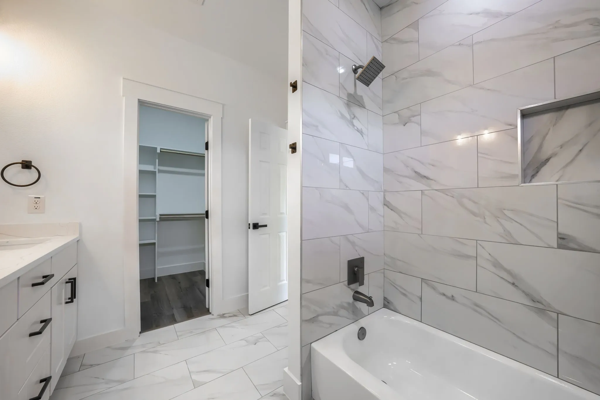 White vanity with dark hardware, stone countertop, and integrated sink