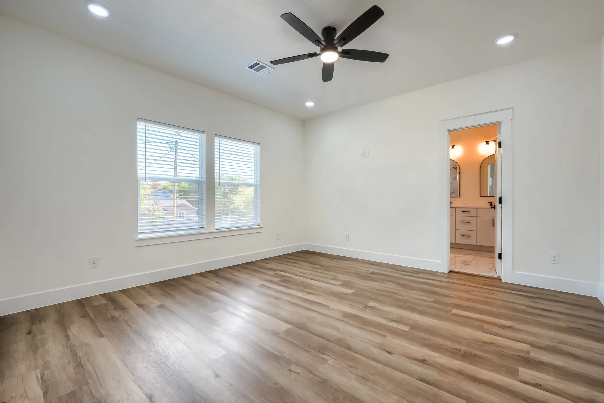 Spacious room featuring wood-finish flooring, recessed lighting, a ceiling fan, and two windows with blinds