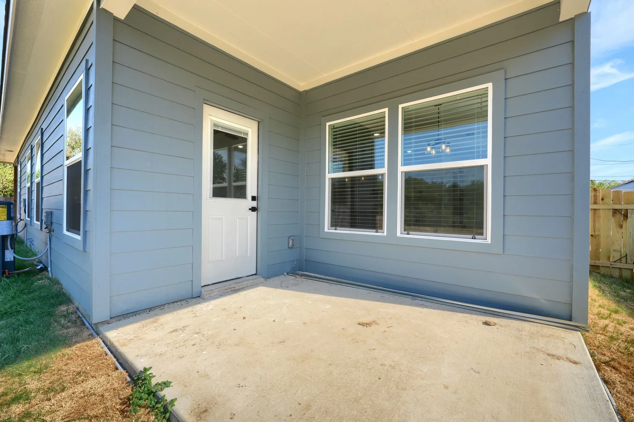 Exterior featuring a concrete patio, blue siding, white trim, and multiple windows