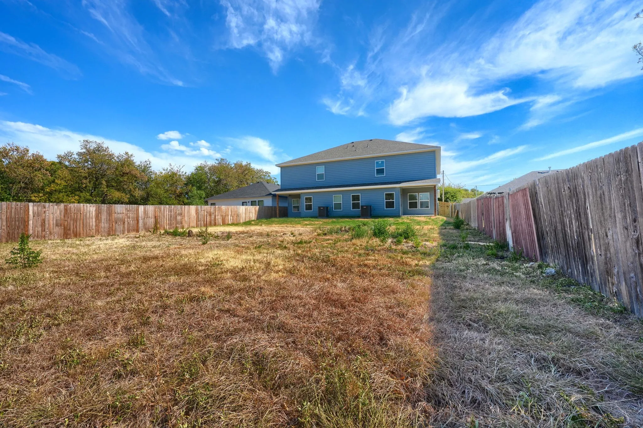 Expansive backyard with wood fencing and a two-story exterior