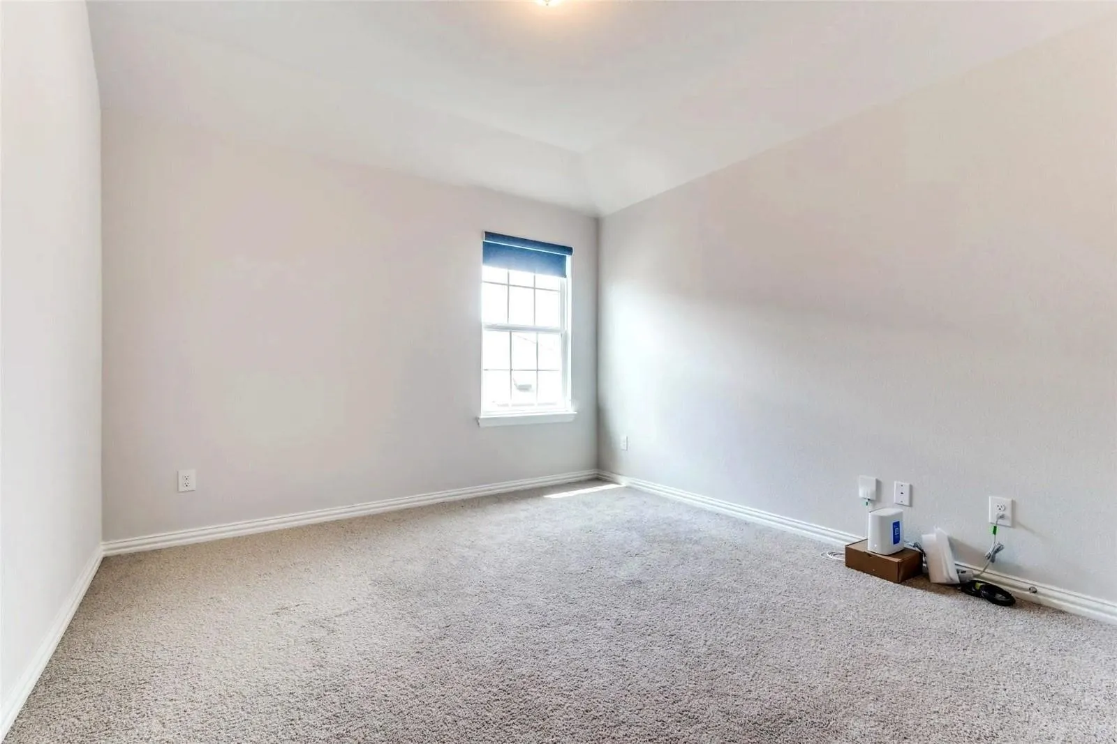 Carpeted room with a single window, featuring a tray ceiling and light-toned walls