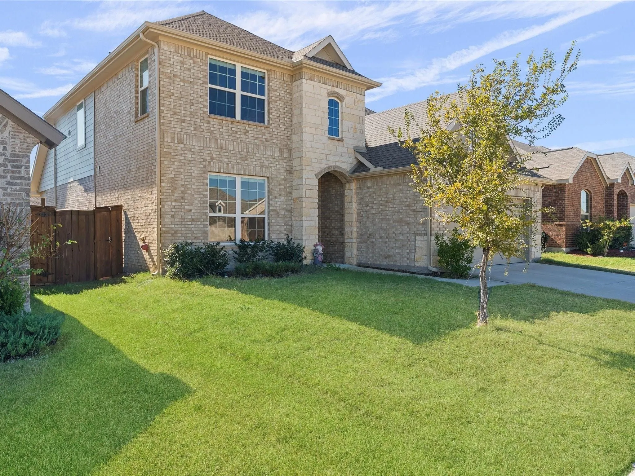 Two-story residence featuring a brick and stone facade, arched entryway, and attached garage