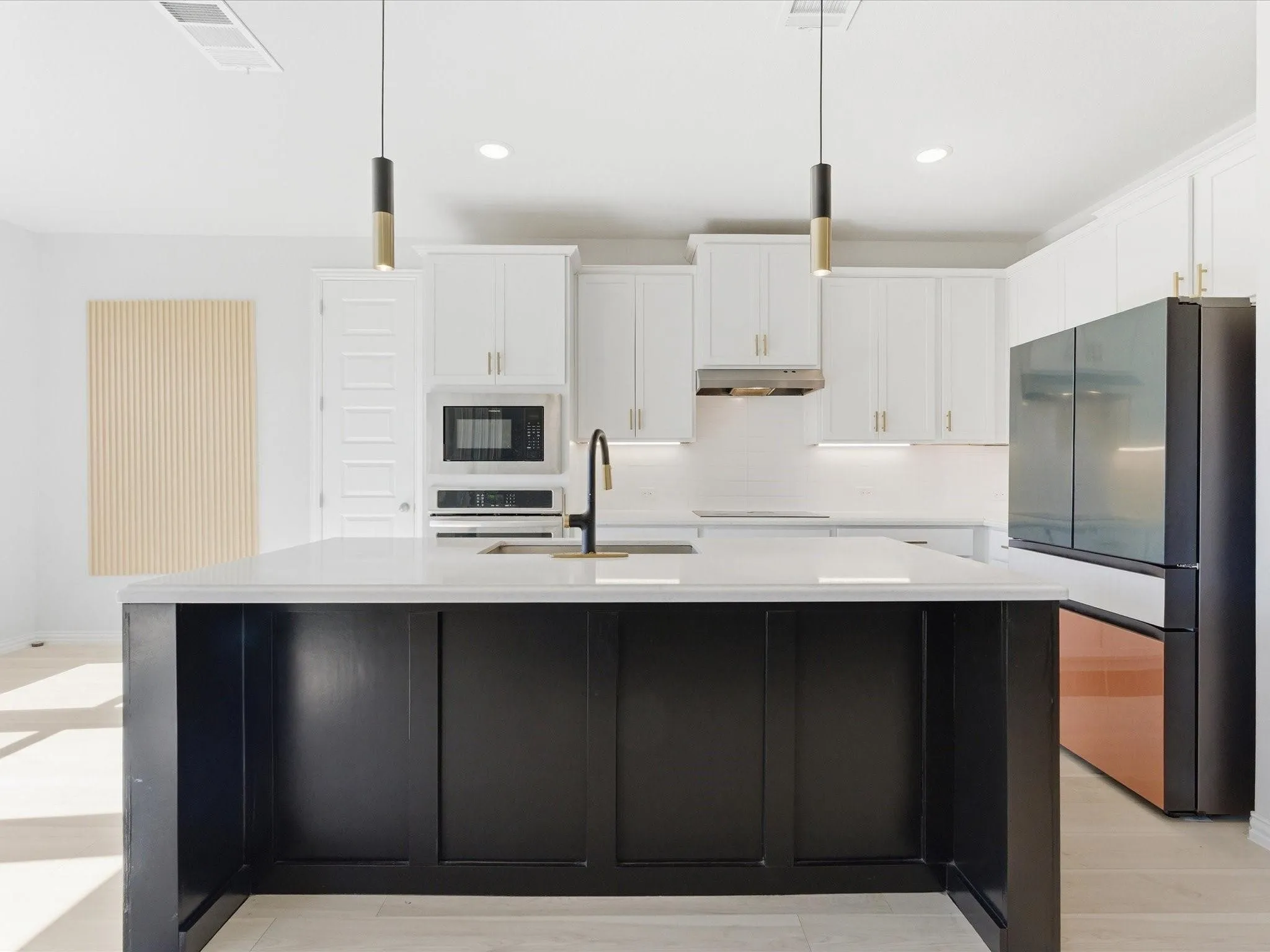 Modern kitchen featuring a contrasting island with a light-colored countertop, white upper and lower cabinetry, built-in microwave, and a black and copper-toned refrigerator