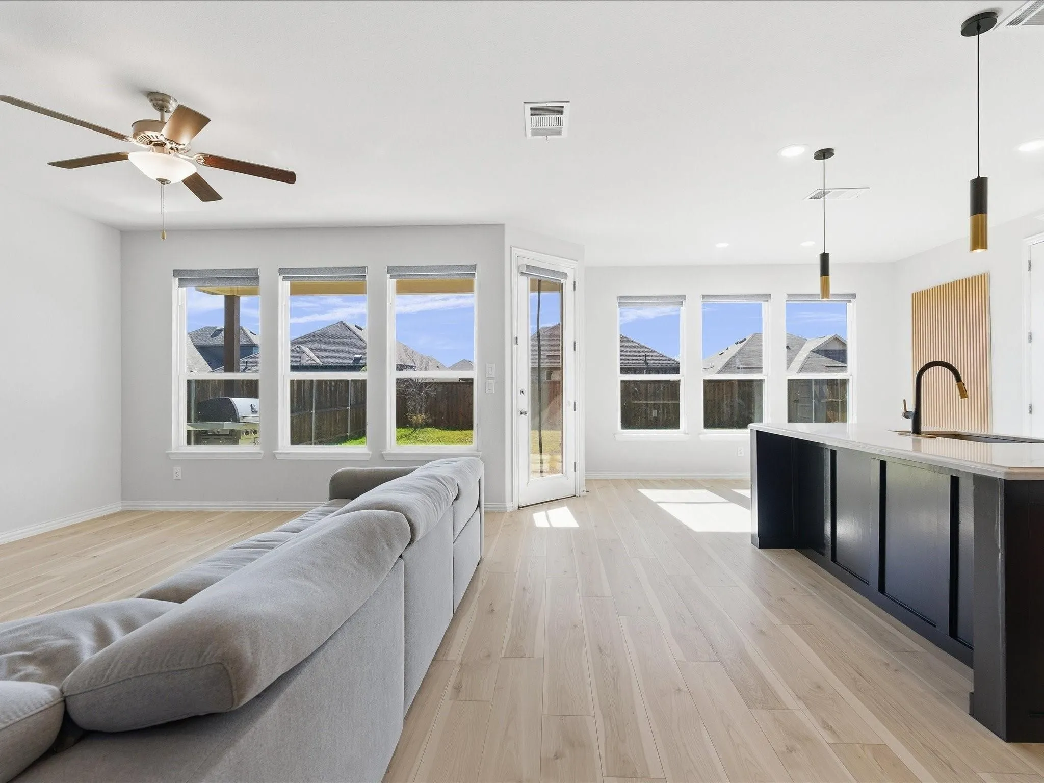 Open-concept living space featuring wood-finish flooring, recessed lighting, and multiple windows