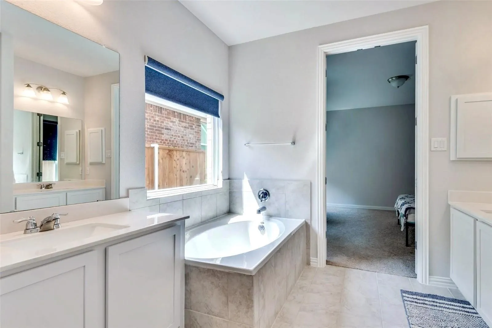 Dual sink vanity with white cabinetry and integrated mirror