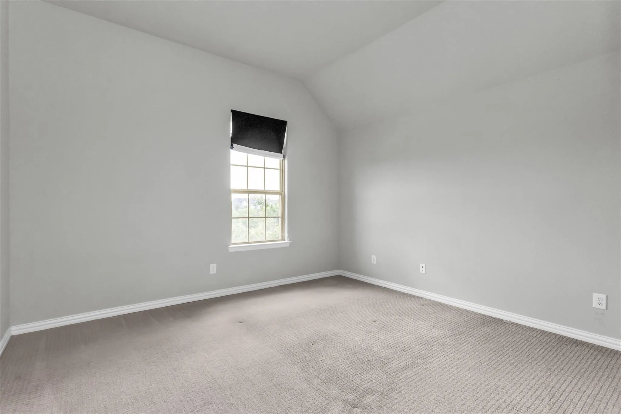 Neutral wall finish, carpeted flooring, window with sash, and sloped ceiling