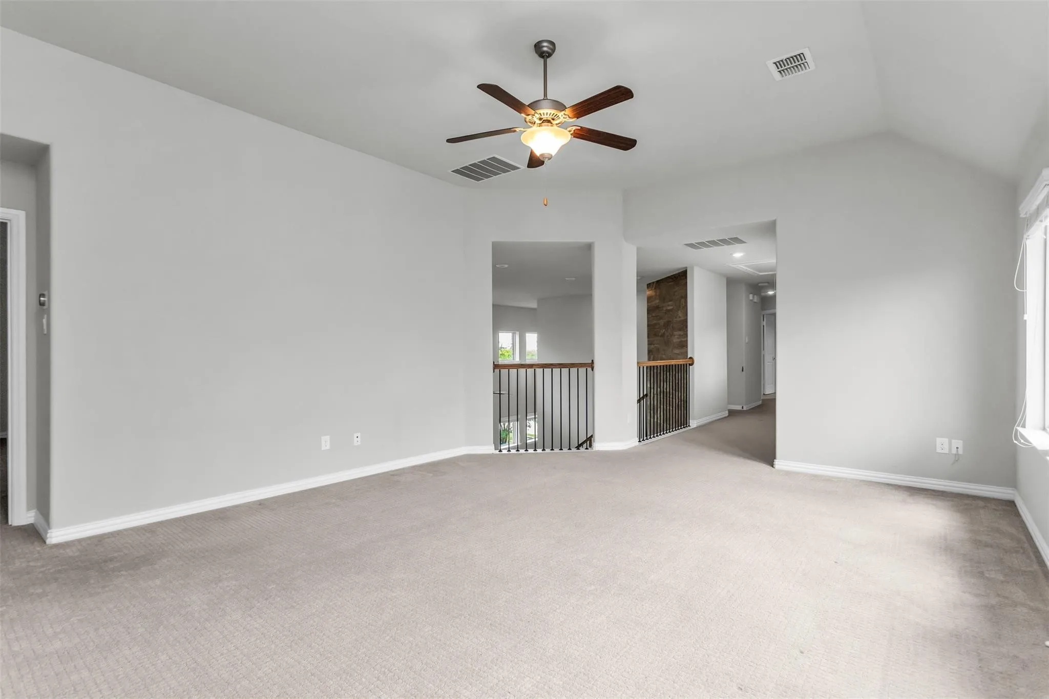Carpeted room with a vaulted ceiling, ceiling fan with integrated lighting, and a window with blinds