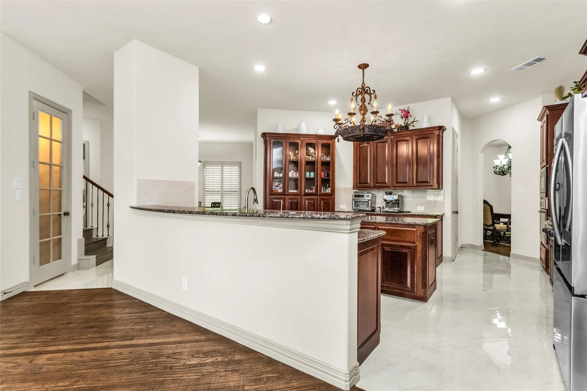 Kitchen featuring rich wood cabinetry, stone countertops, a large chandelier, and stainless steel appliances