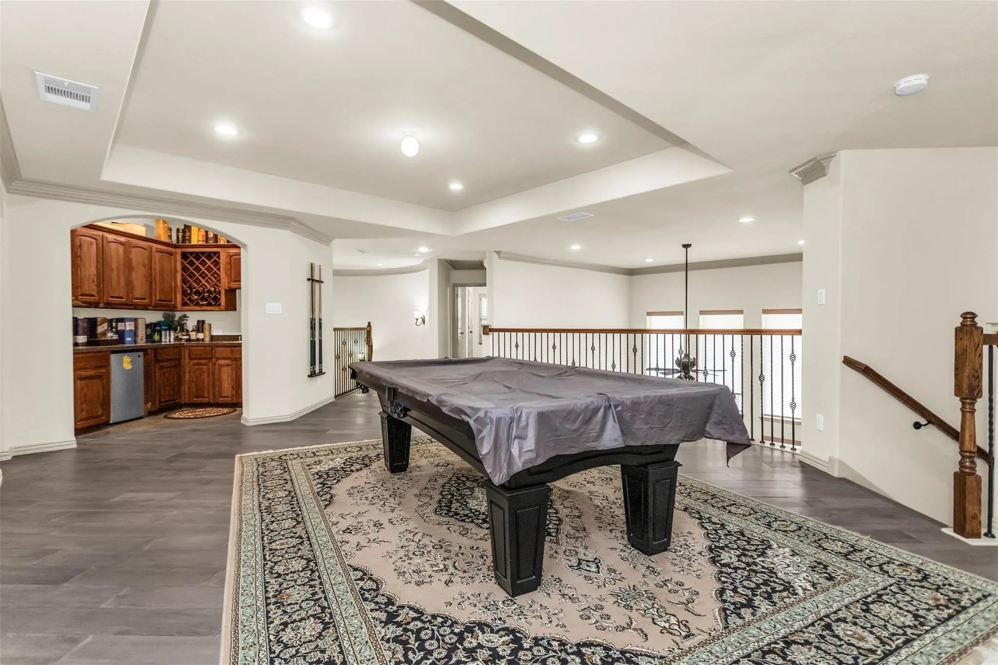 Spacious second-story landing featuring recessed lighting, a built-in wet bar with wood cabinetry and a wine rack, and dark wood-finish flooring
