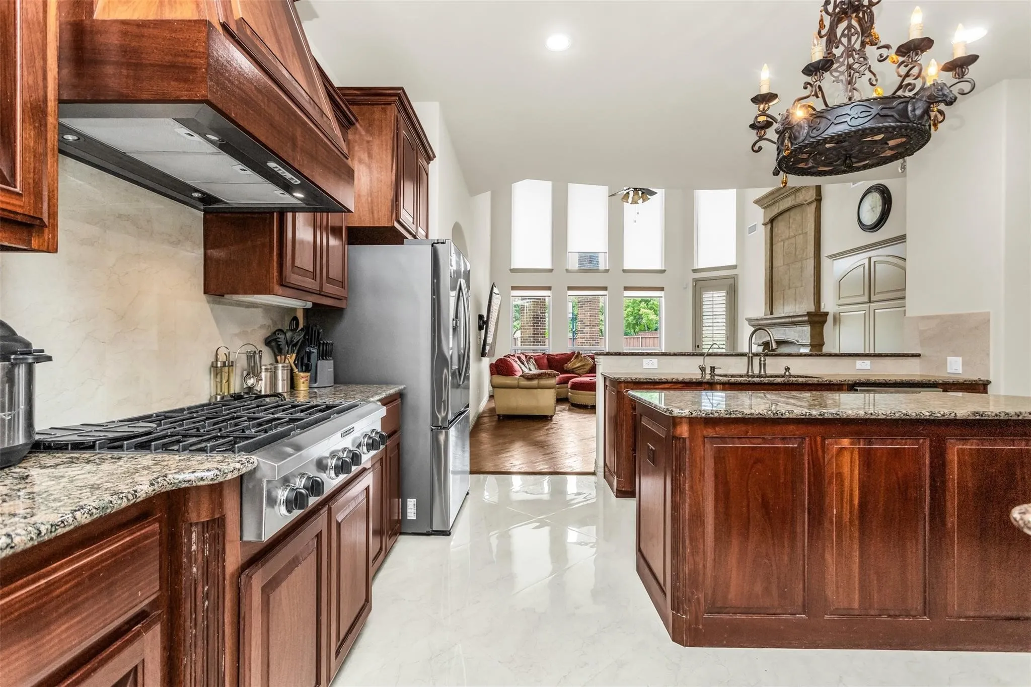 Gourmet kitchen with stainless steel gas range, wood cabinetry, granite countertops, and tile flooring