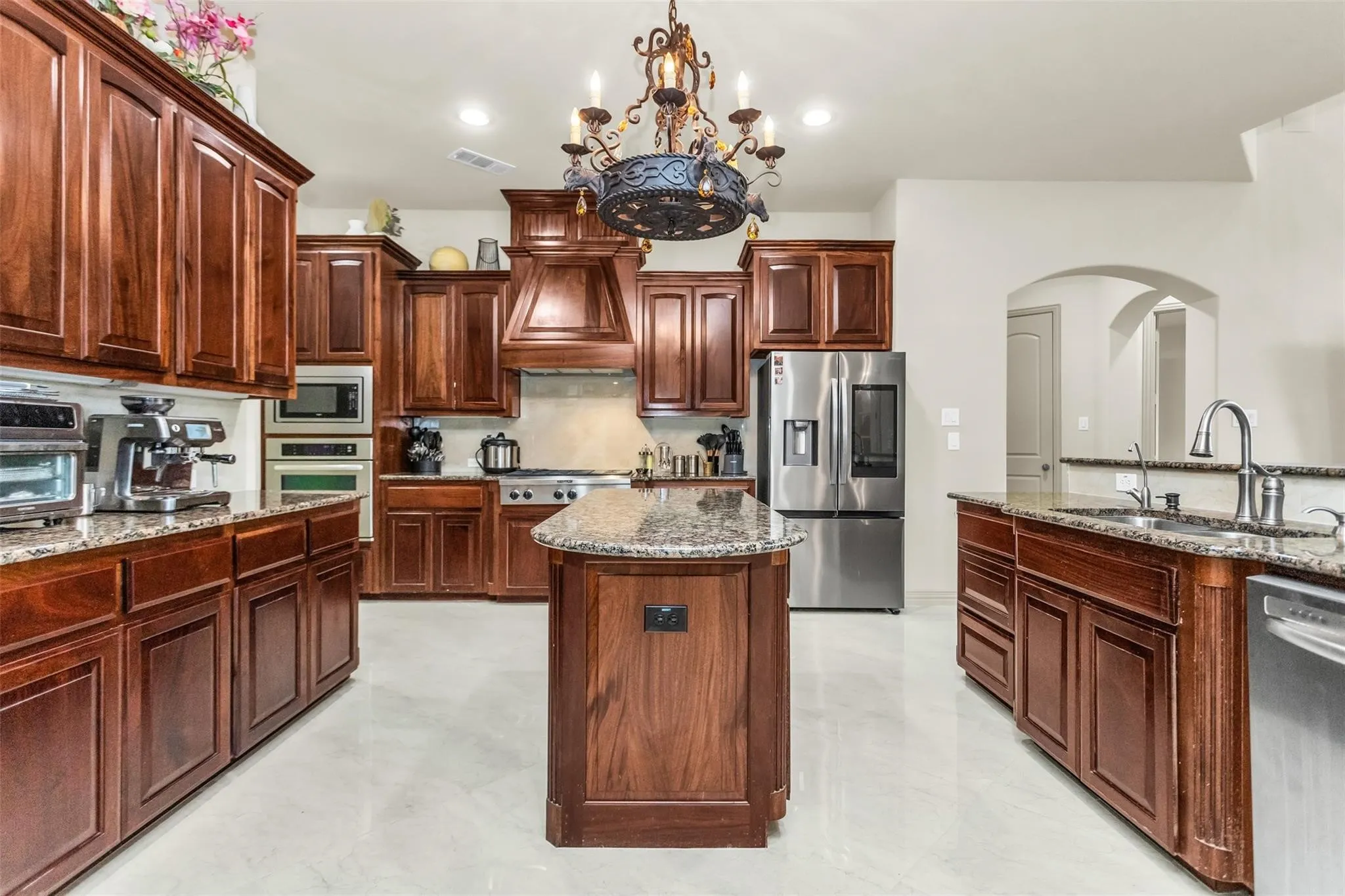 Gourmet kitchen featuring extensive wood cabinetry, stainless steel appliances, an island with a stone countertop, and recessed lighting