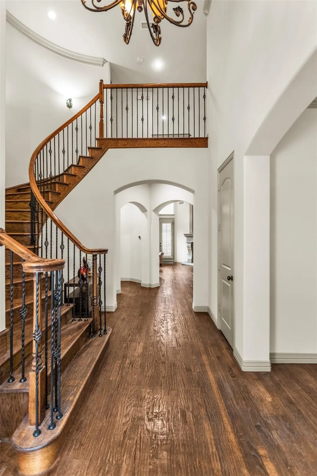 Grand foyer featuring a wood-finish staircase with wrought iron balusters, high ceilings, recessed lighting, and archways