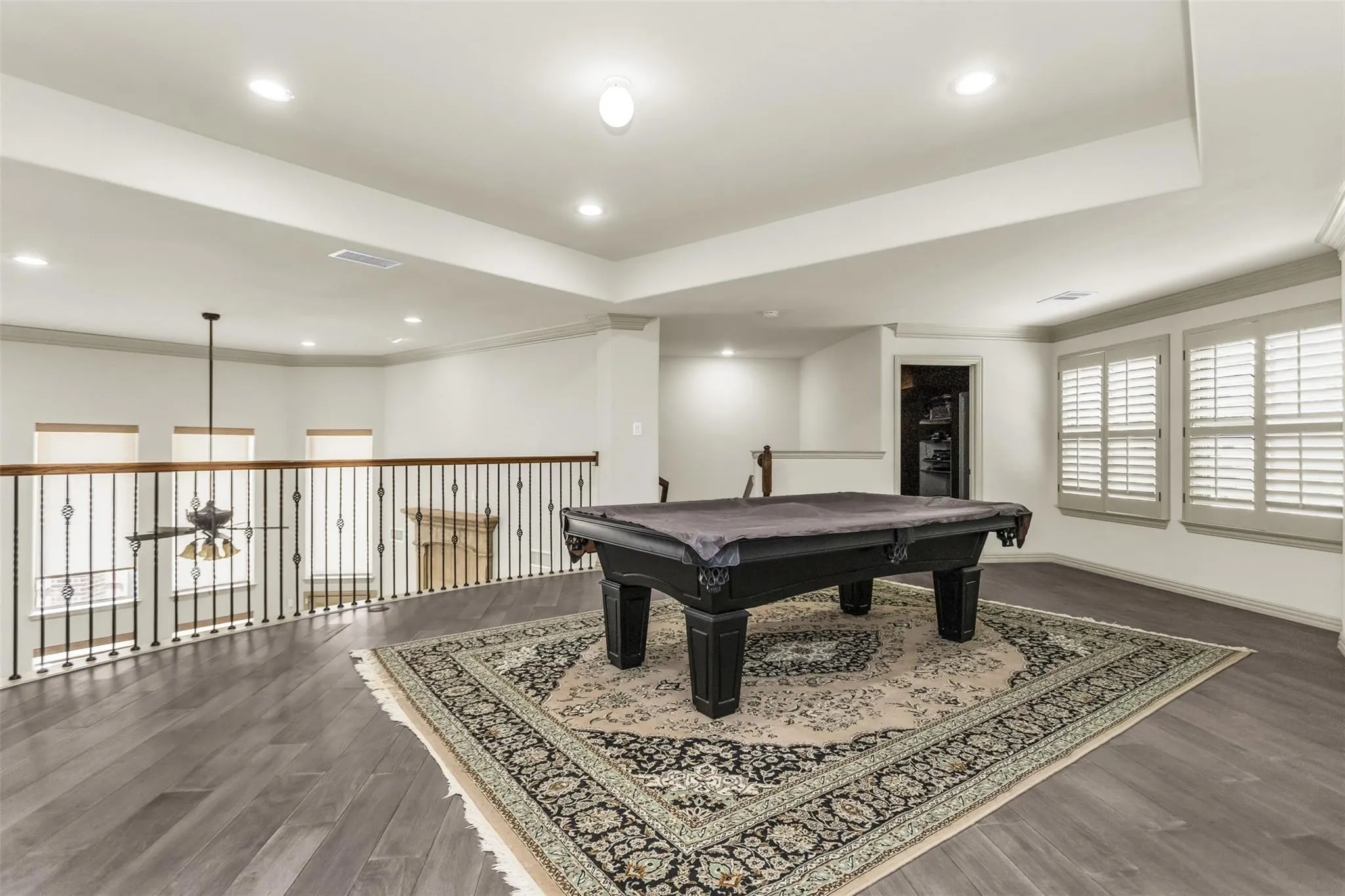 Expansive loft area featuring wood-finish flooring, recessed lighting, and white plantation shutters