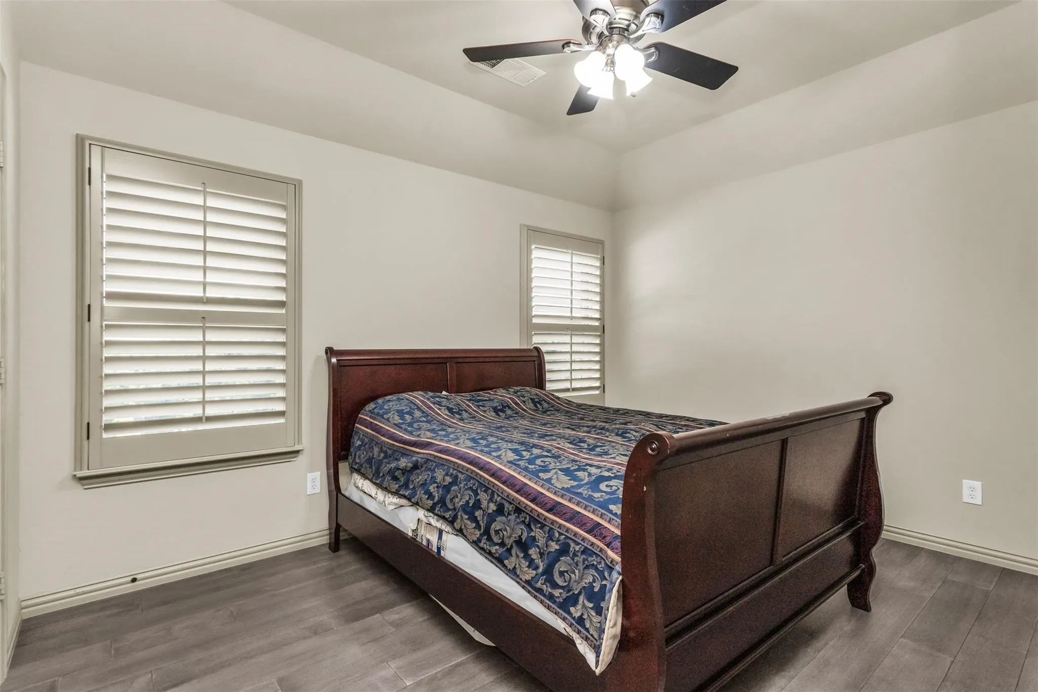 Wood-finish flooring, plantation shutters, and a ceiling fan with integrated lighting