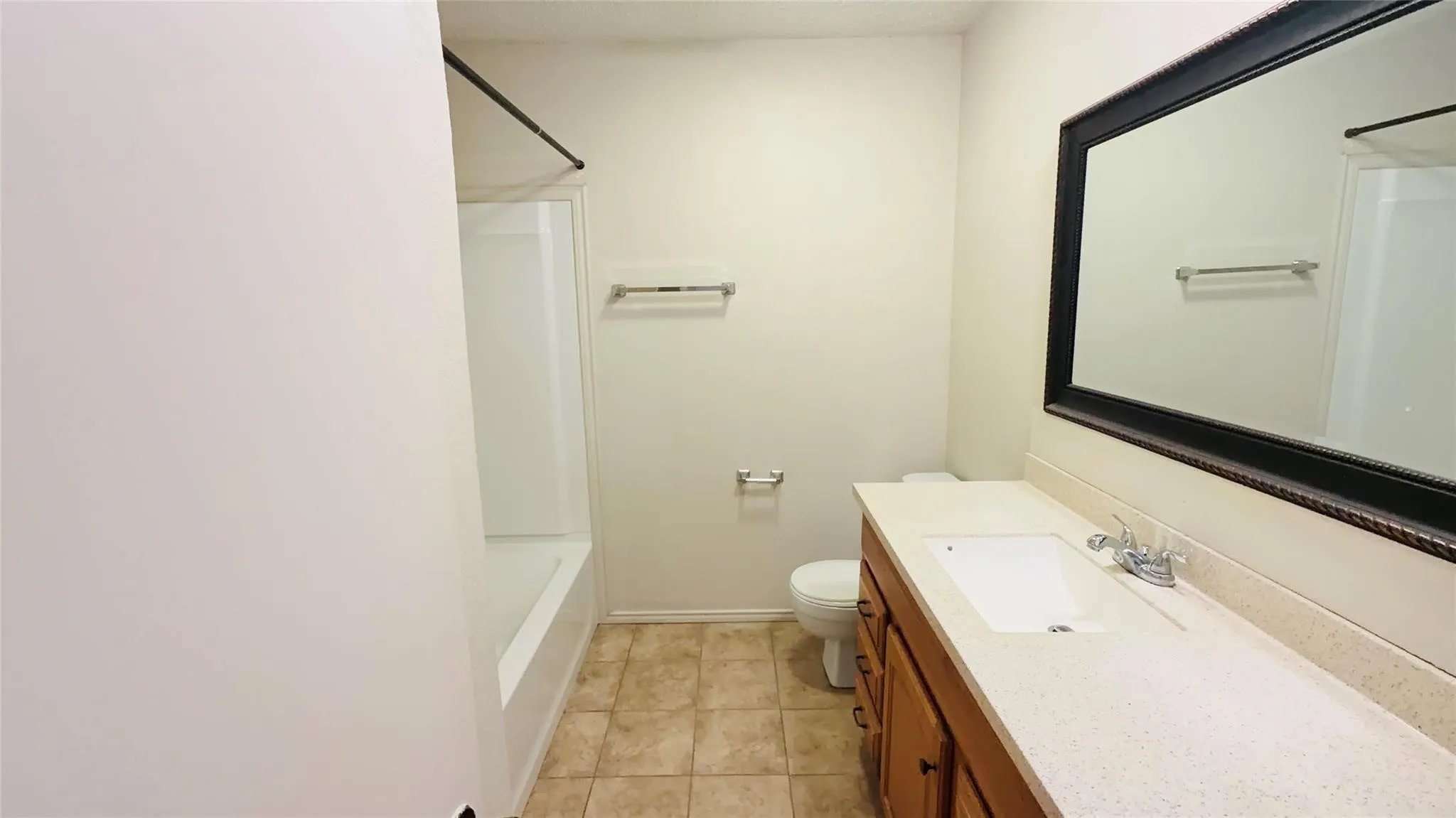 Bathroom featuring a full vanity with an integrated sink, framed mirror, and a shower-tub combination