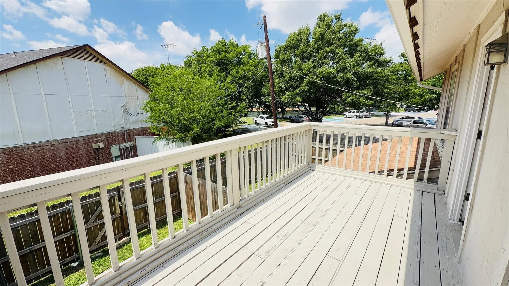 Outdoor deck space with a wood privacy fence and exterior wall lantern