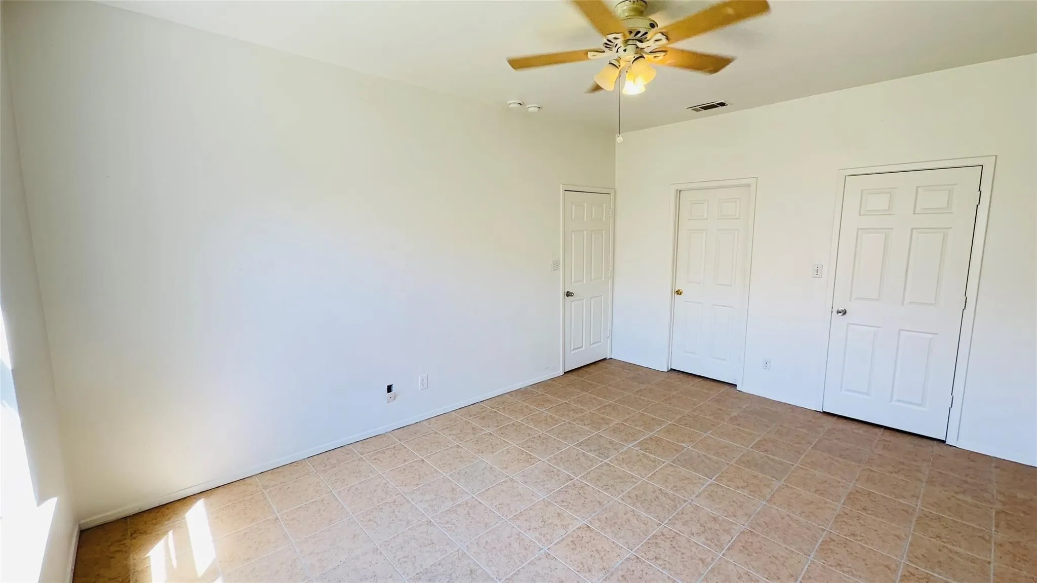 Room featuring white walls, tile flooring, and a ceiling fan with integrated lighting