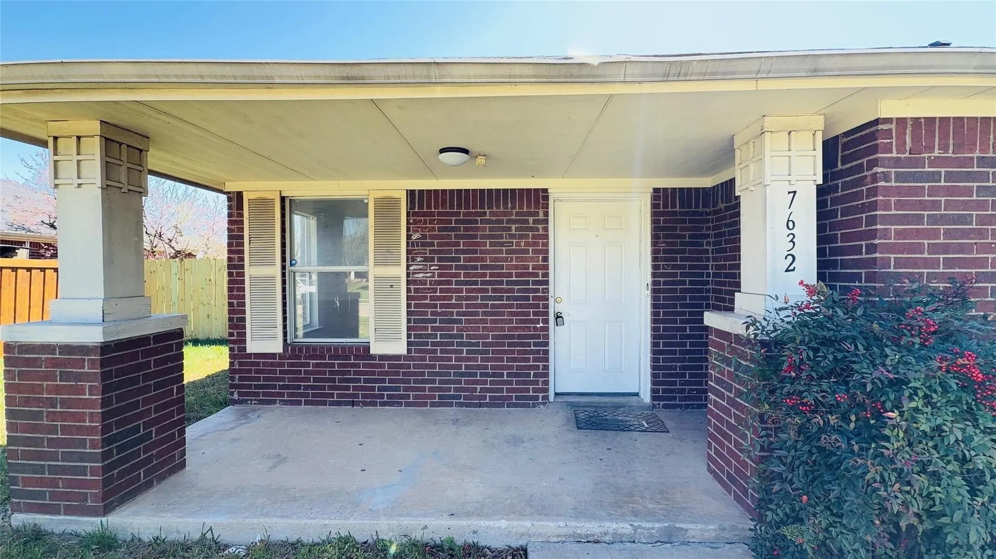 Brick exterior with a covered porch, decorative porch columns, and a front entry door