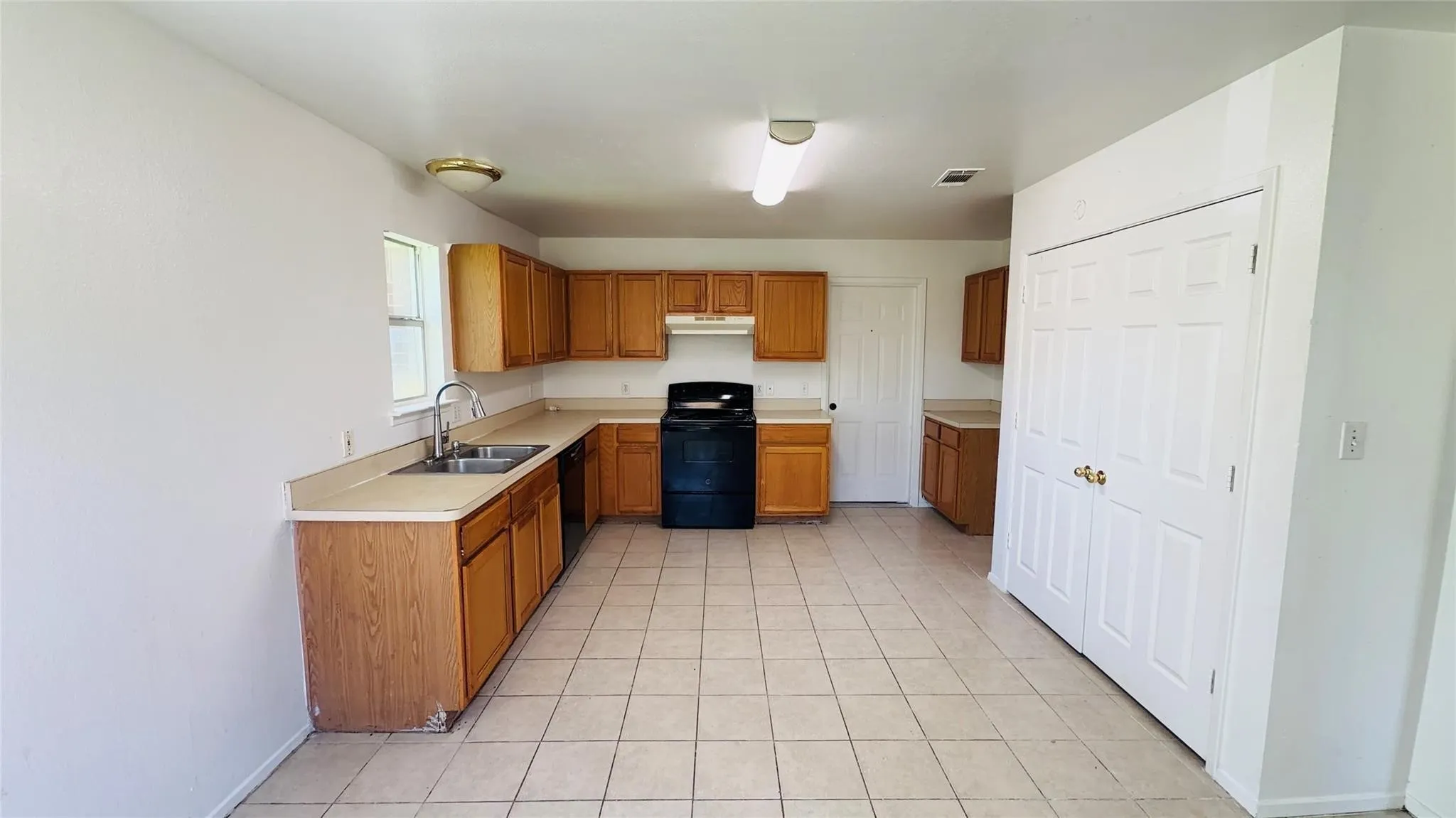 Kitchen featuring wood cabinetry, tile flooring, and a double-basin sink