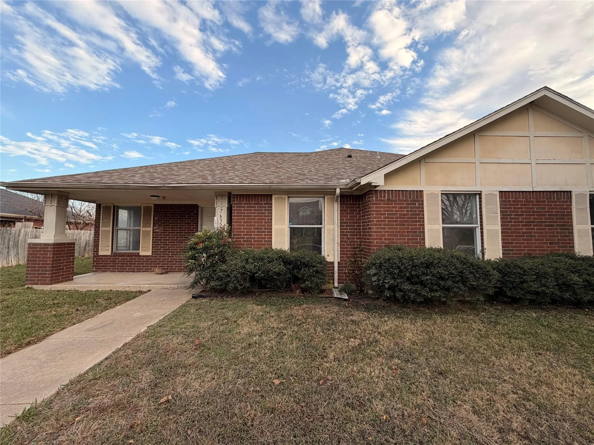 Brick exterior with a gabled roofline, covered entry, and established foundation plantings