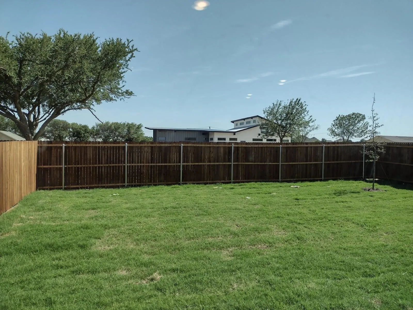 Expansive grassy yard area with a wood privacy fence