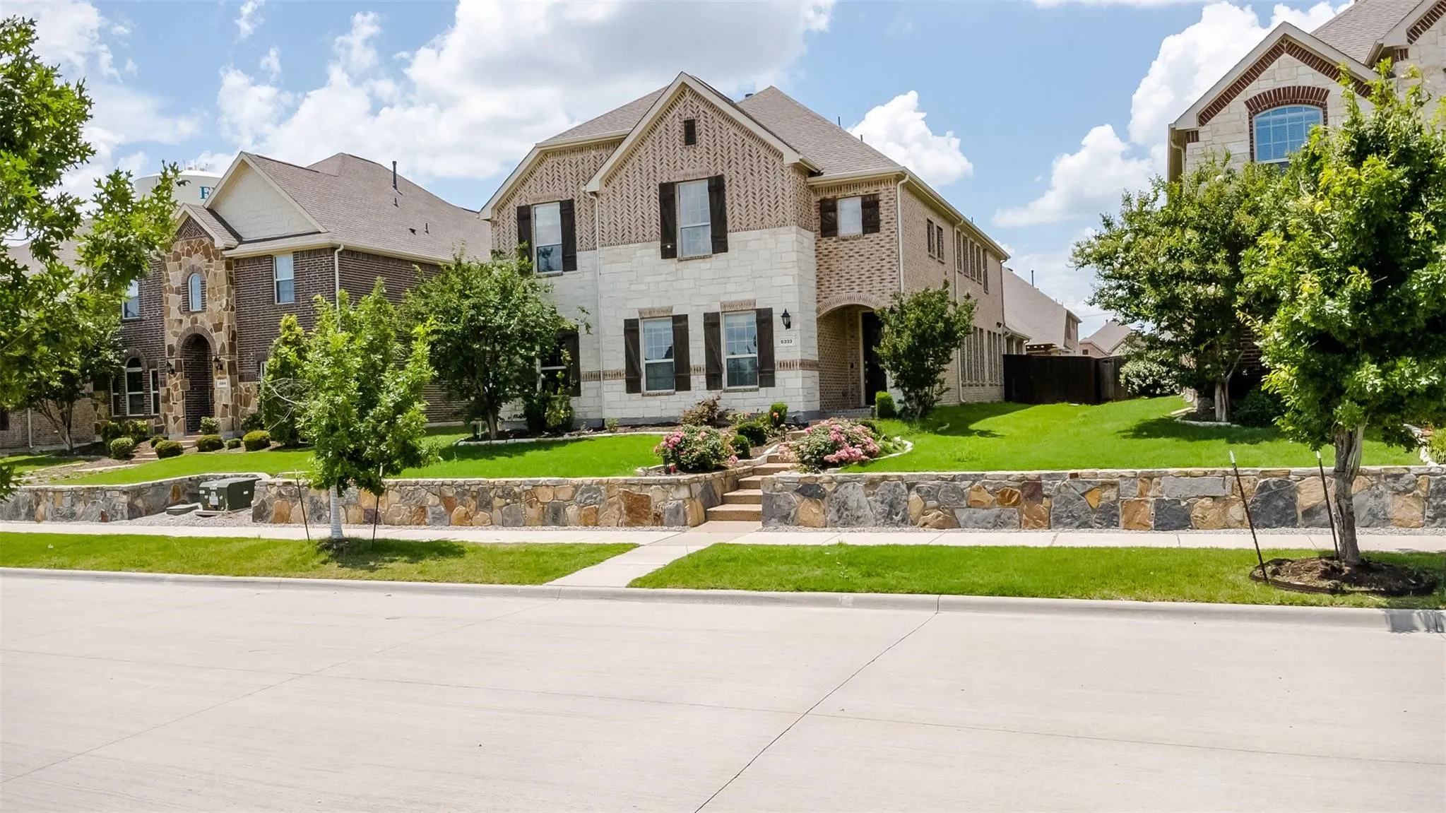 Two-story exterior with a combination of brick and stone facade, complemented by dark shutters and a gabled roof