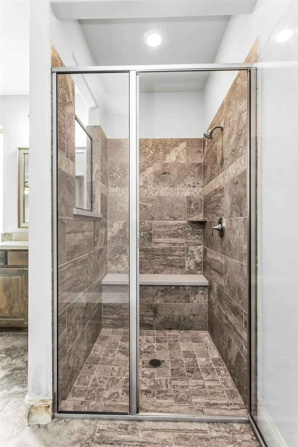 Enclosed shower with glass paneling, tile flooring, built-in tile bench, and an integrated shower niche