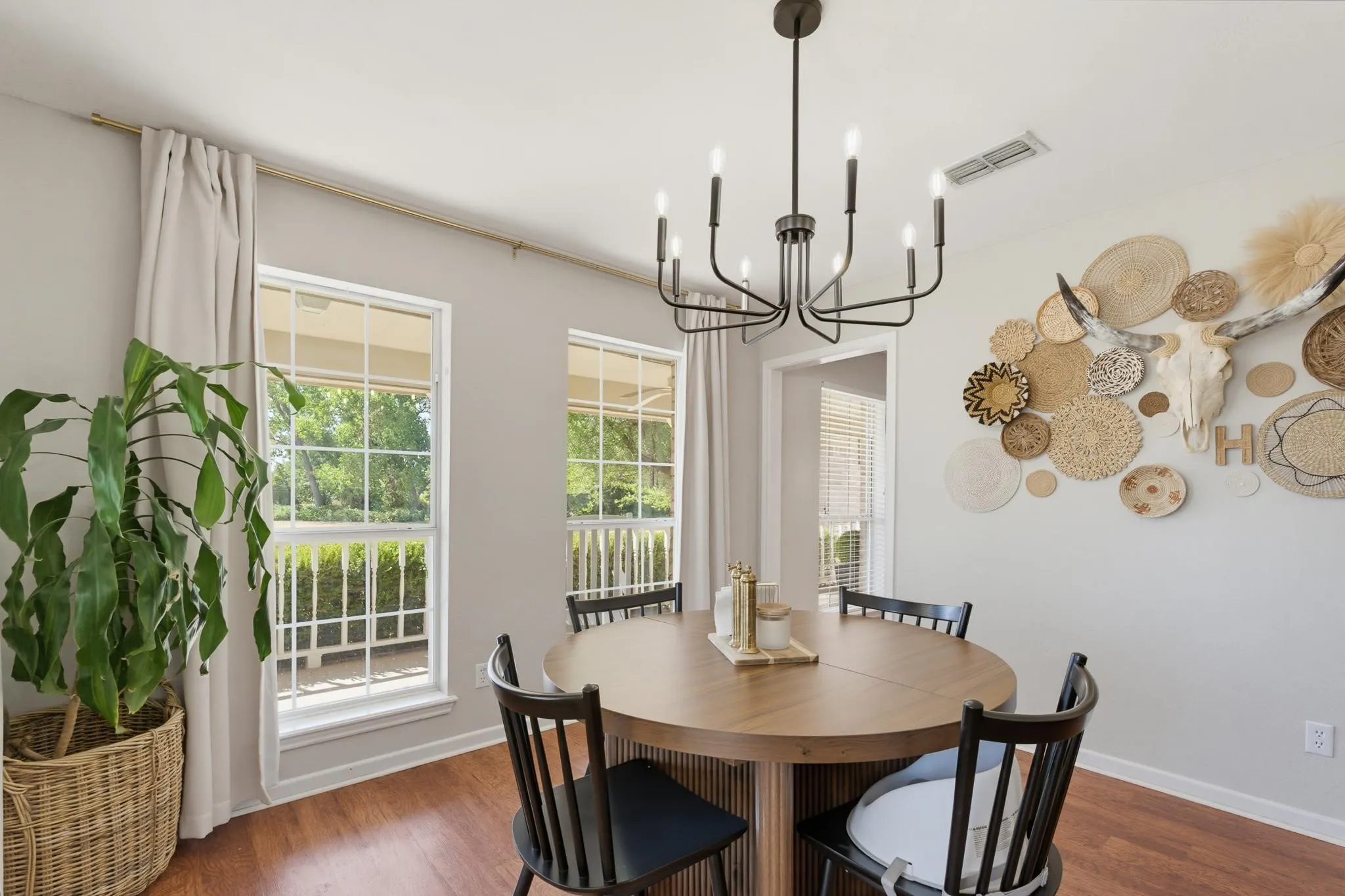 Wood-finish flooring, white trim, and a black chandelier