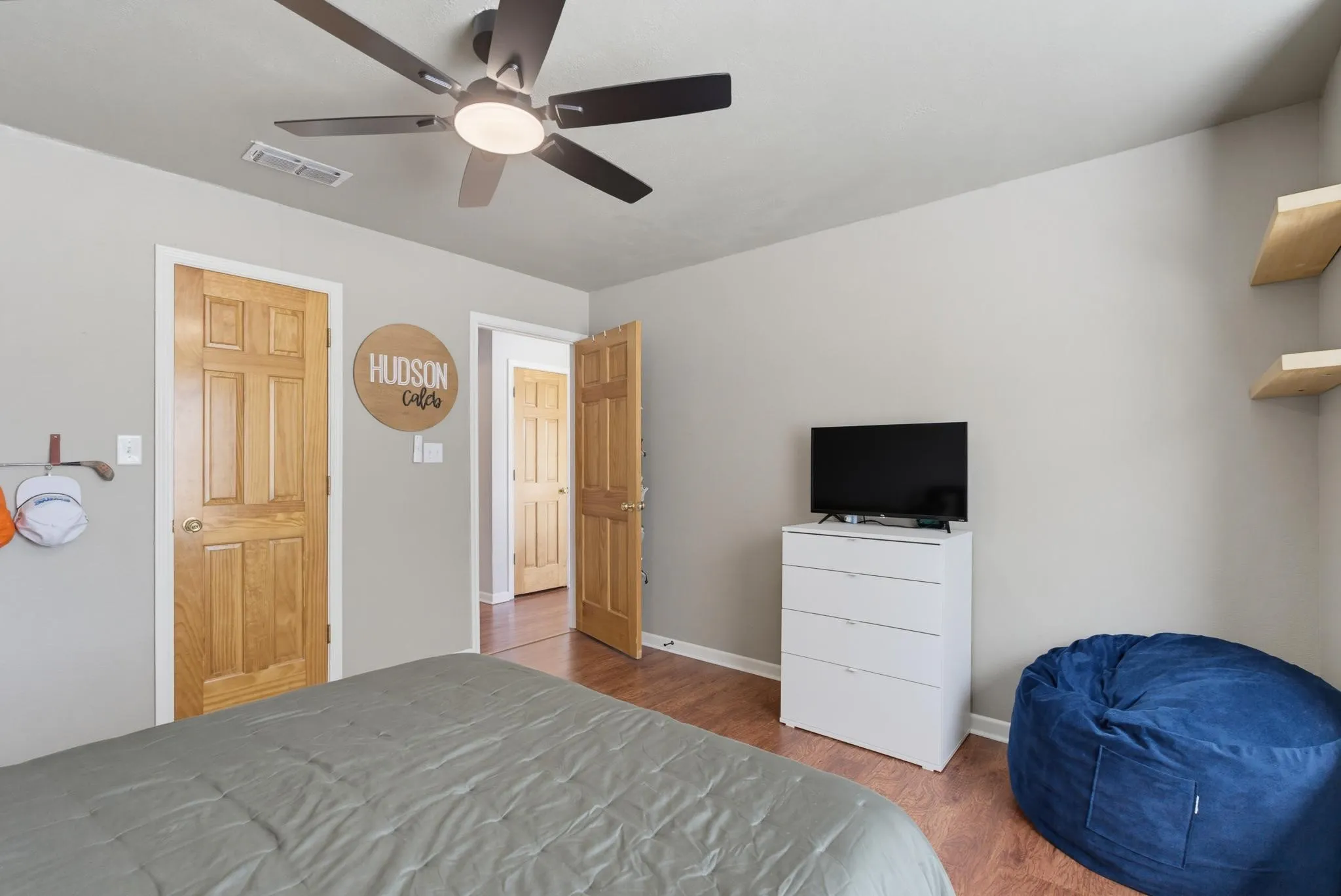 Wood-finish flooring, light grey wall paint, and a ceiling fan with integrated lighting