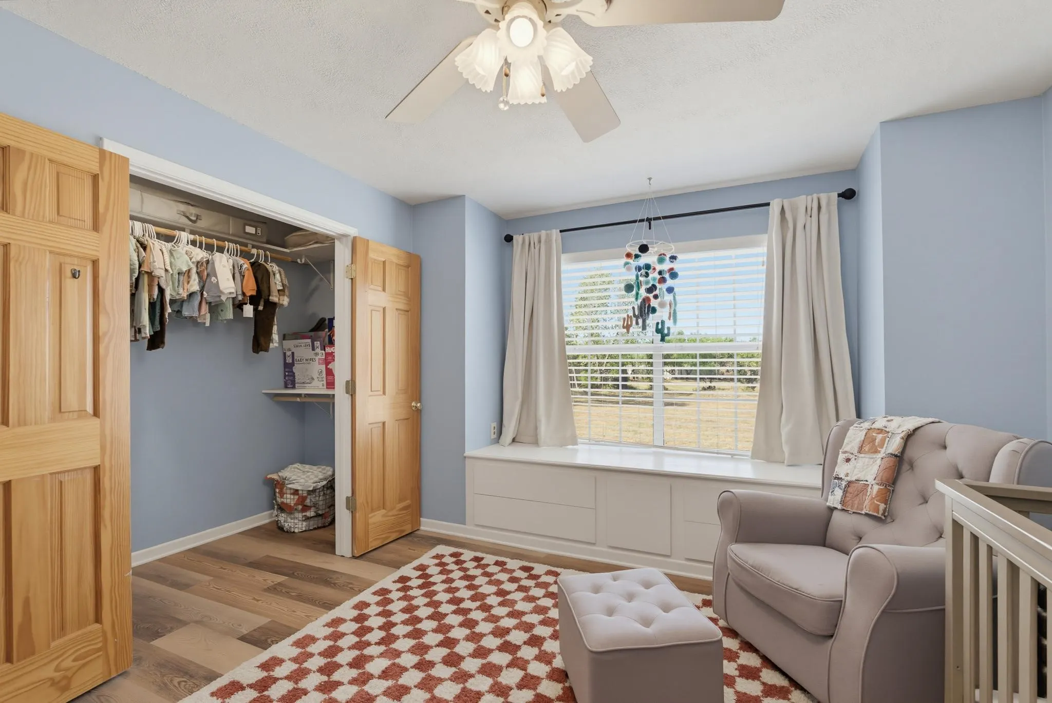 Wood-finish flooring, built-in window seating with integrated storage, and a ceiling fan
