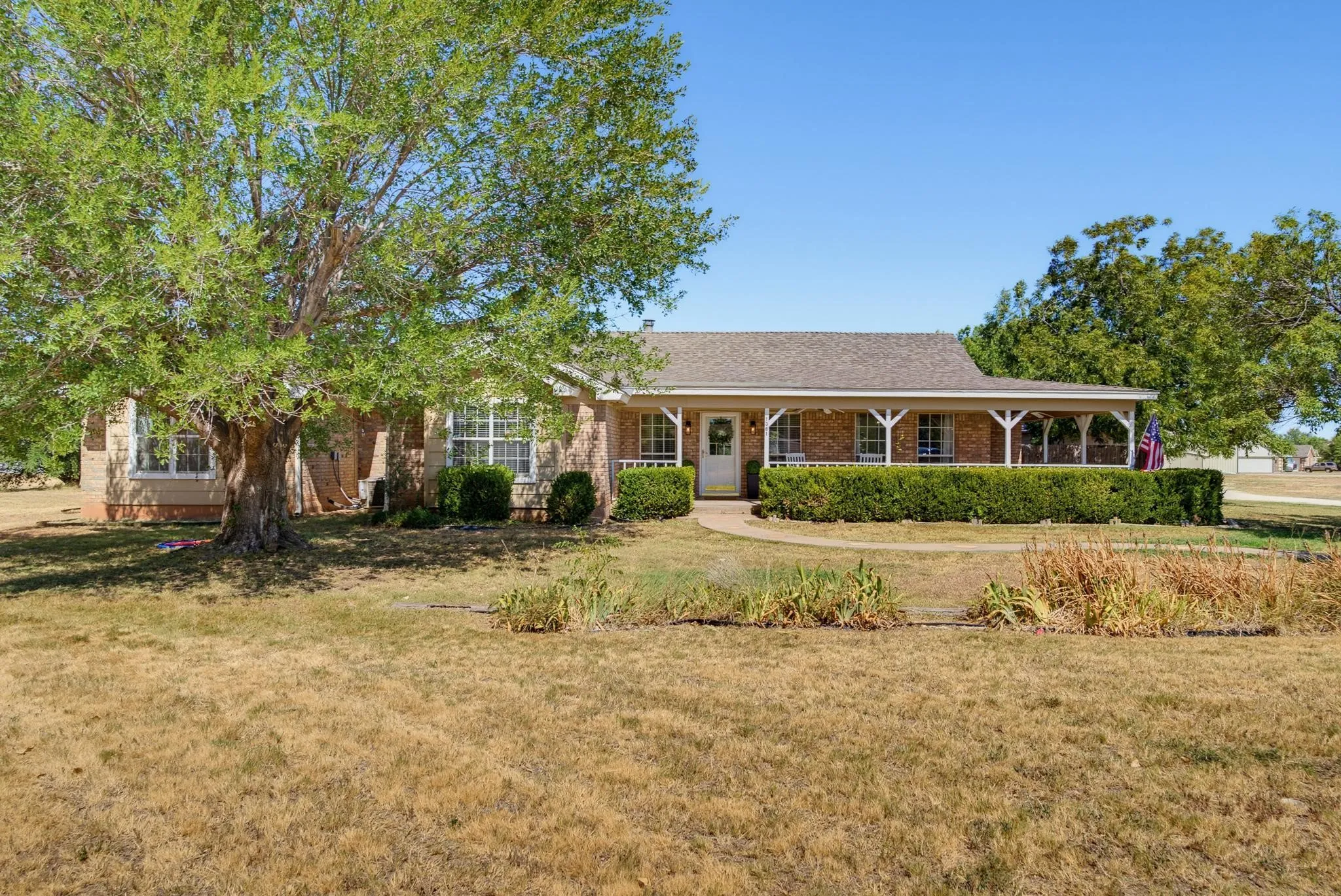 Brick exterior with a covered front porch featuring white columns and a shingle roof