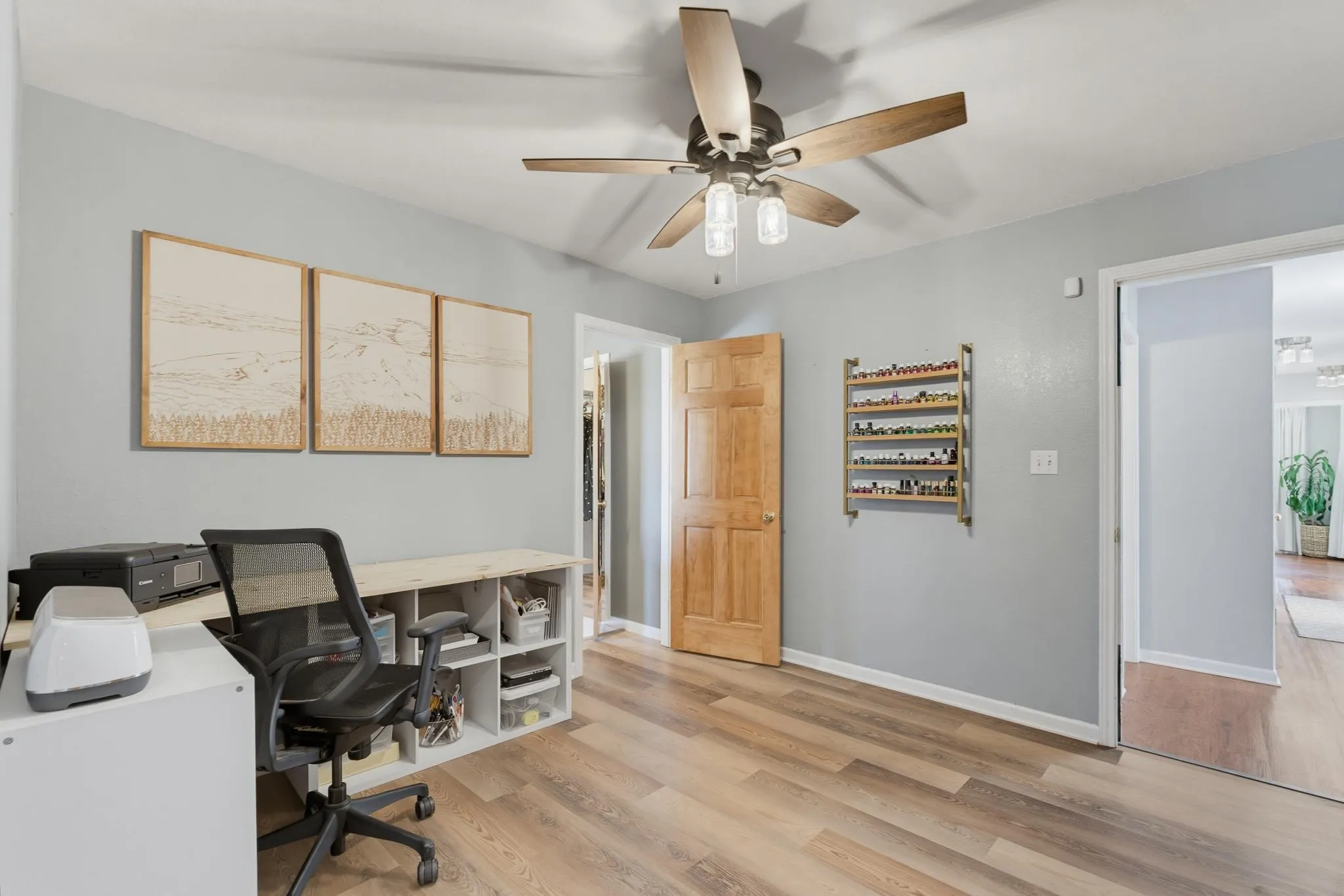 Wood-finish flooring, light gray walls, ceiling fan with light fixture, and a solid wood interior door