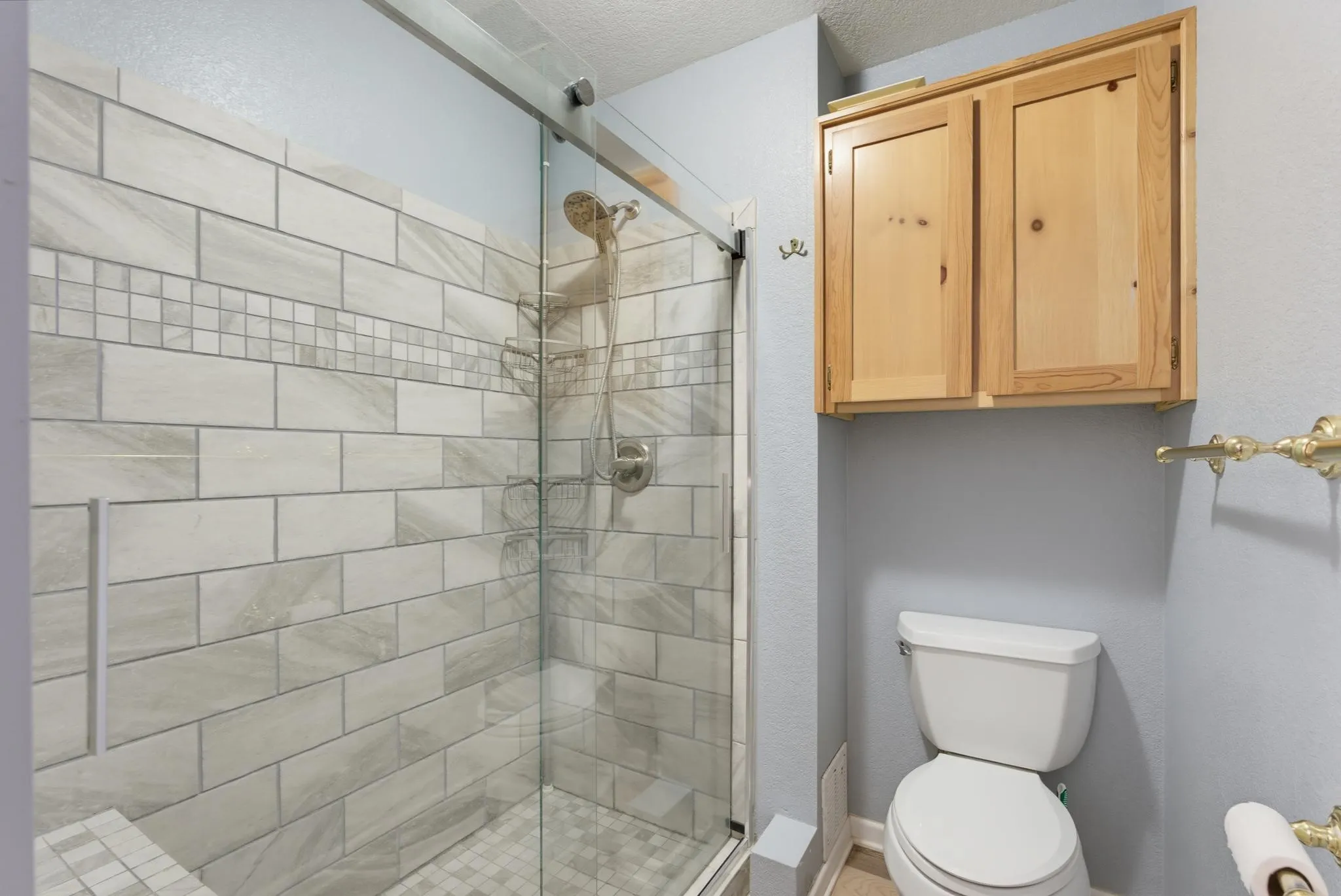 Glass-enclosed shower with tile surround and integrated bench