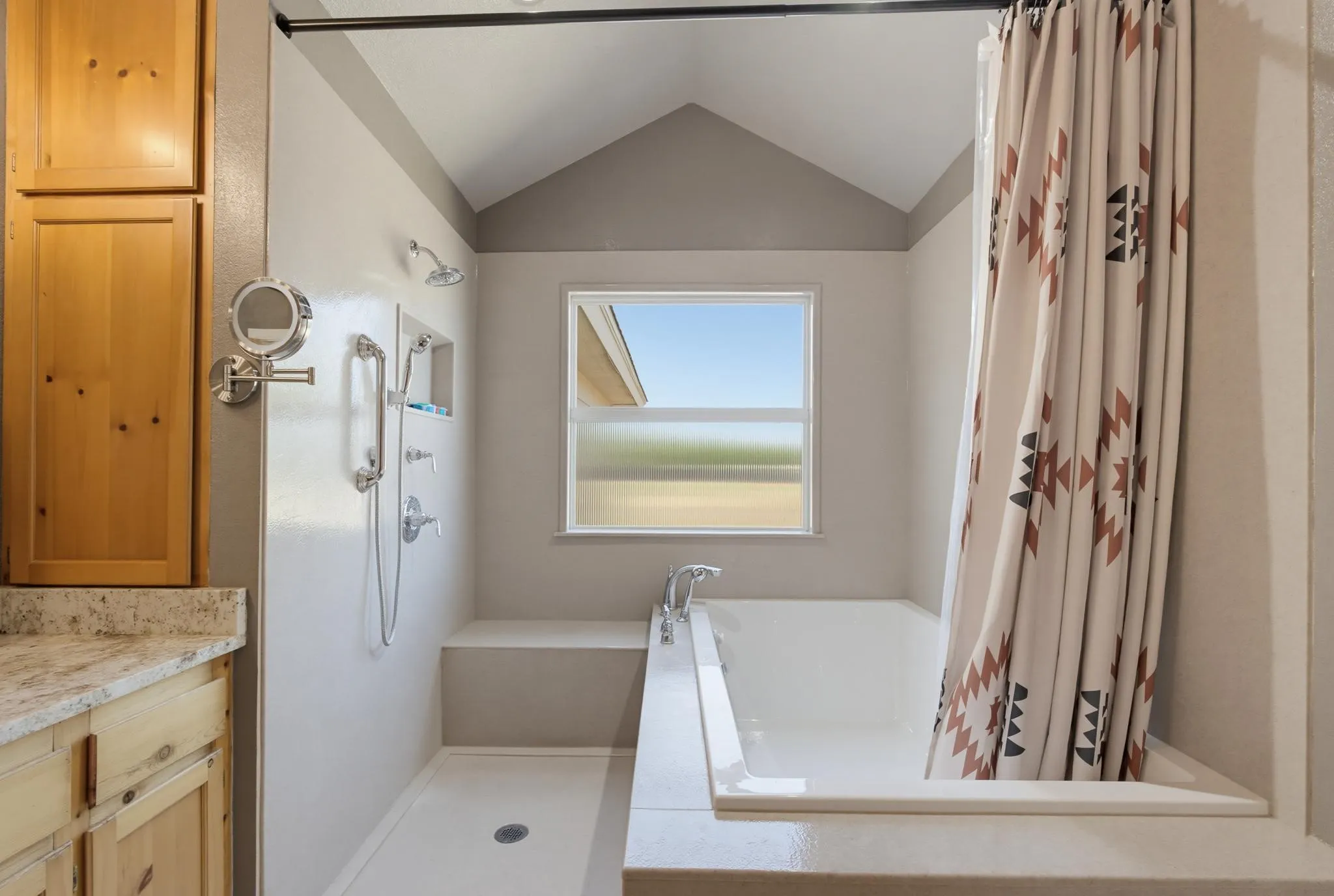 Vaulted ceiling with a window, built-in shower bench, recessed shower niche, and a separate bathtub