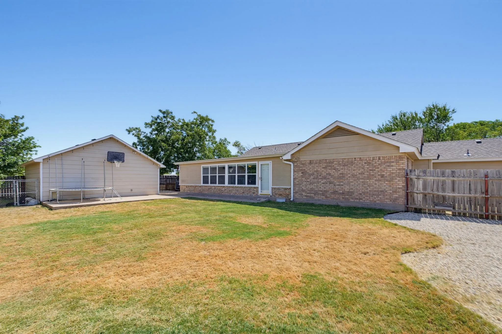 Expansive backyard featuring a detached accessory structure, a paved patio area, and a privacy fence