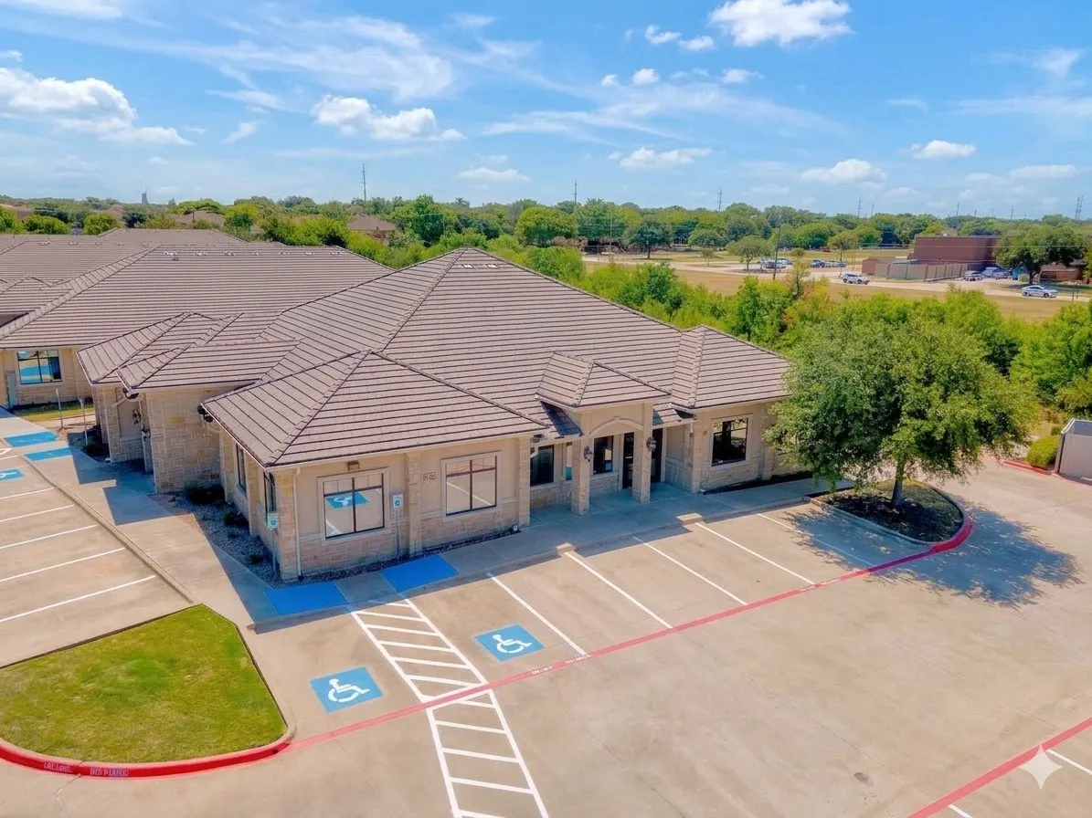 Tile roof, stone exterior, multiple building entrances, dedicated parking, and mature landscaping