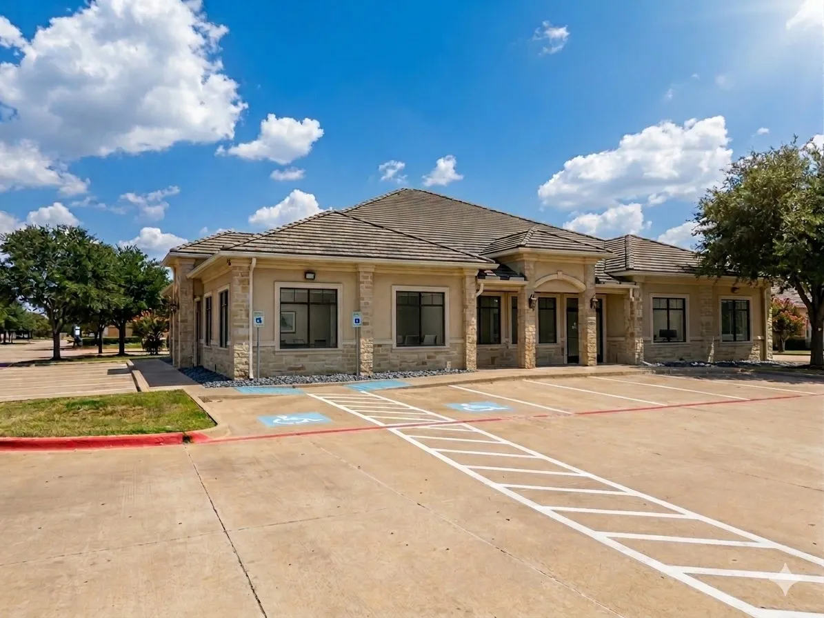 Stone facade building with a multi-gabled roofline, multiple windows, and a dedicated parking area with accessible spaces