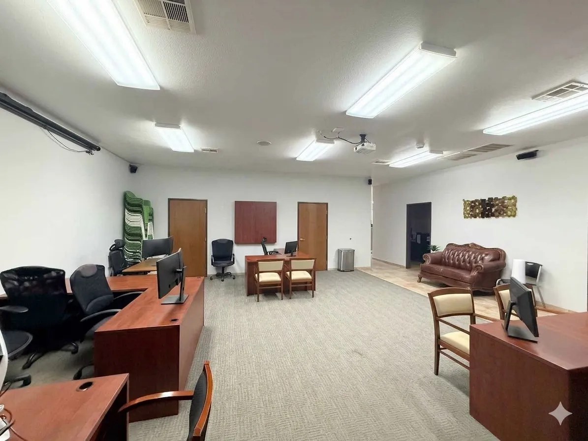 Spacious interior featuring a combination of carpeted and tiled flooring, multiple overhead fluorescent light fixtures, and a ceiling-mounted projector